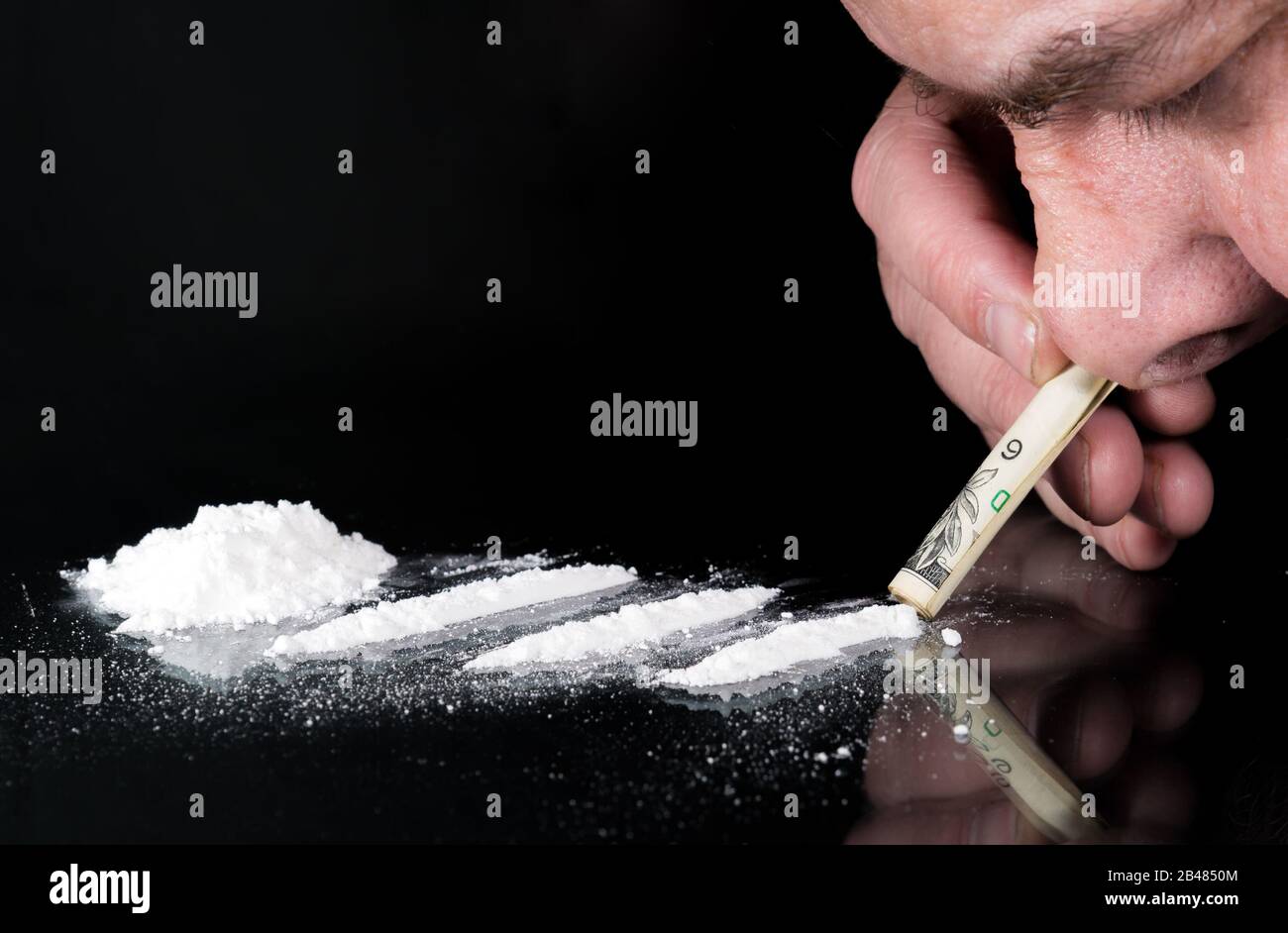 snorting-a-line-of-cocaine-there-are-three-lines-on-a-glass-table-and-a-pile-to-the-left-a-persons-nose-is-snorting-through-a-rolled-bill-2B4850M.jpg